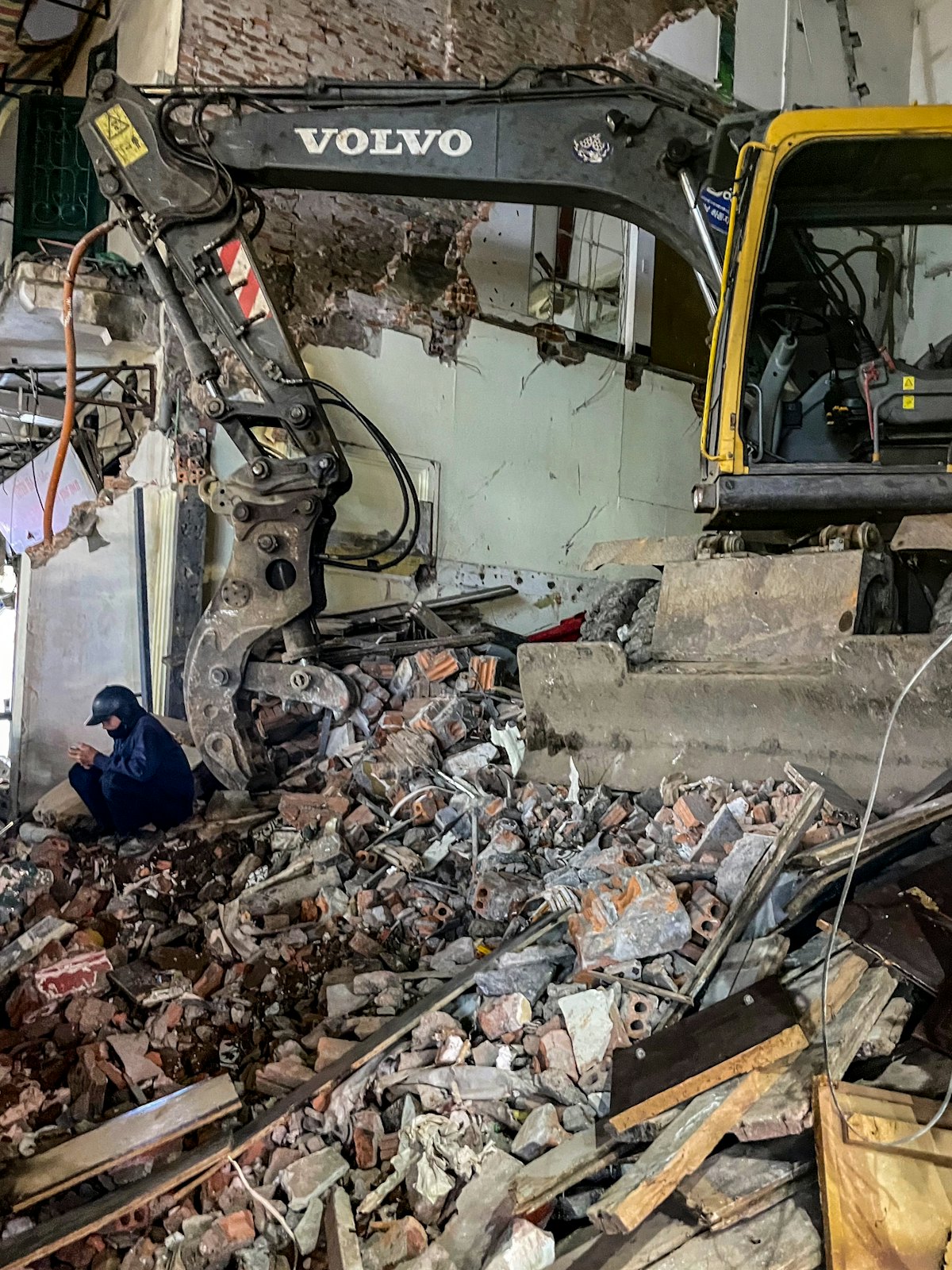 Excavator working through debris at a demolition site