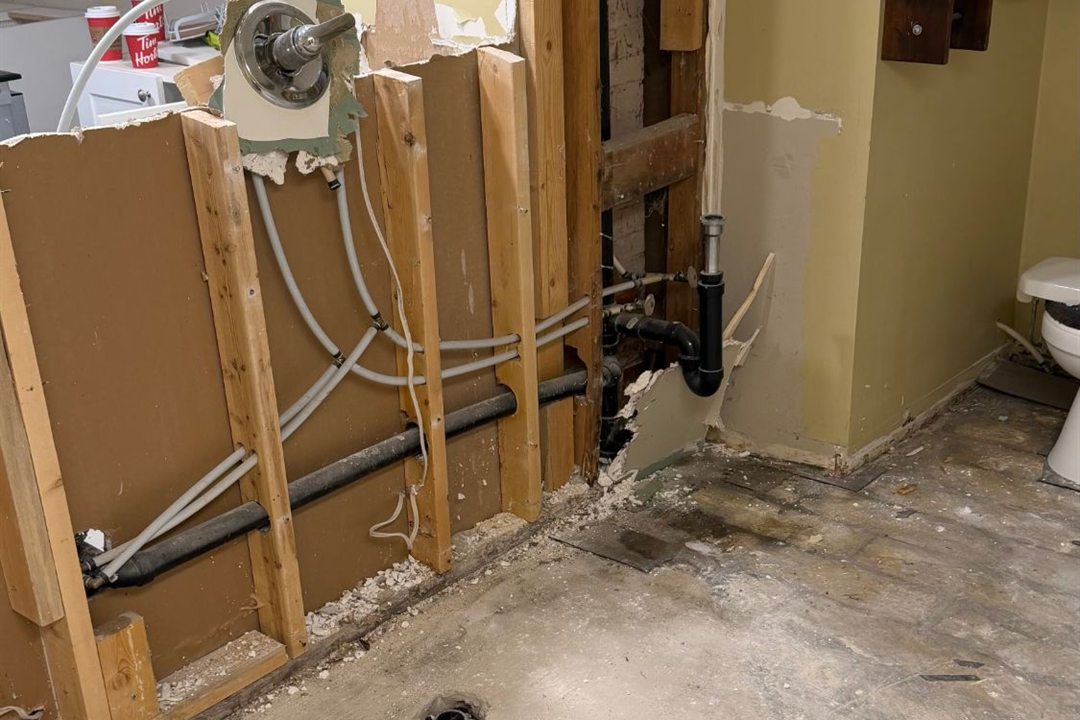 After an interior gut-out by Demolition King Group: drywall and flooring removed, exposing wood studs, plumbing and water lines