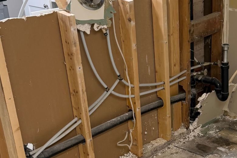Bathroom wall opened to the wood studs and plumbing during a residential interior gut-out by Demolition King Group