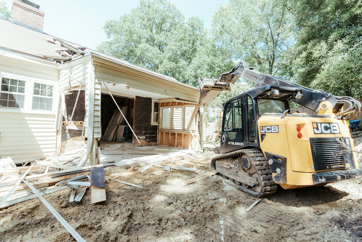 Skid steer beside a partially demolished house