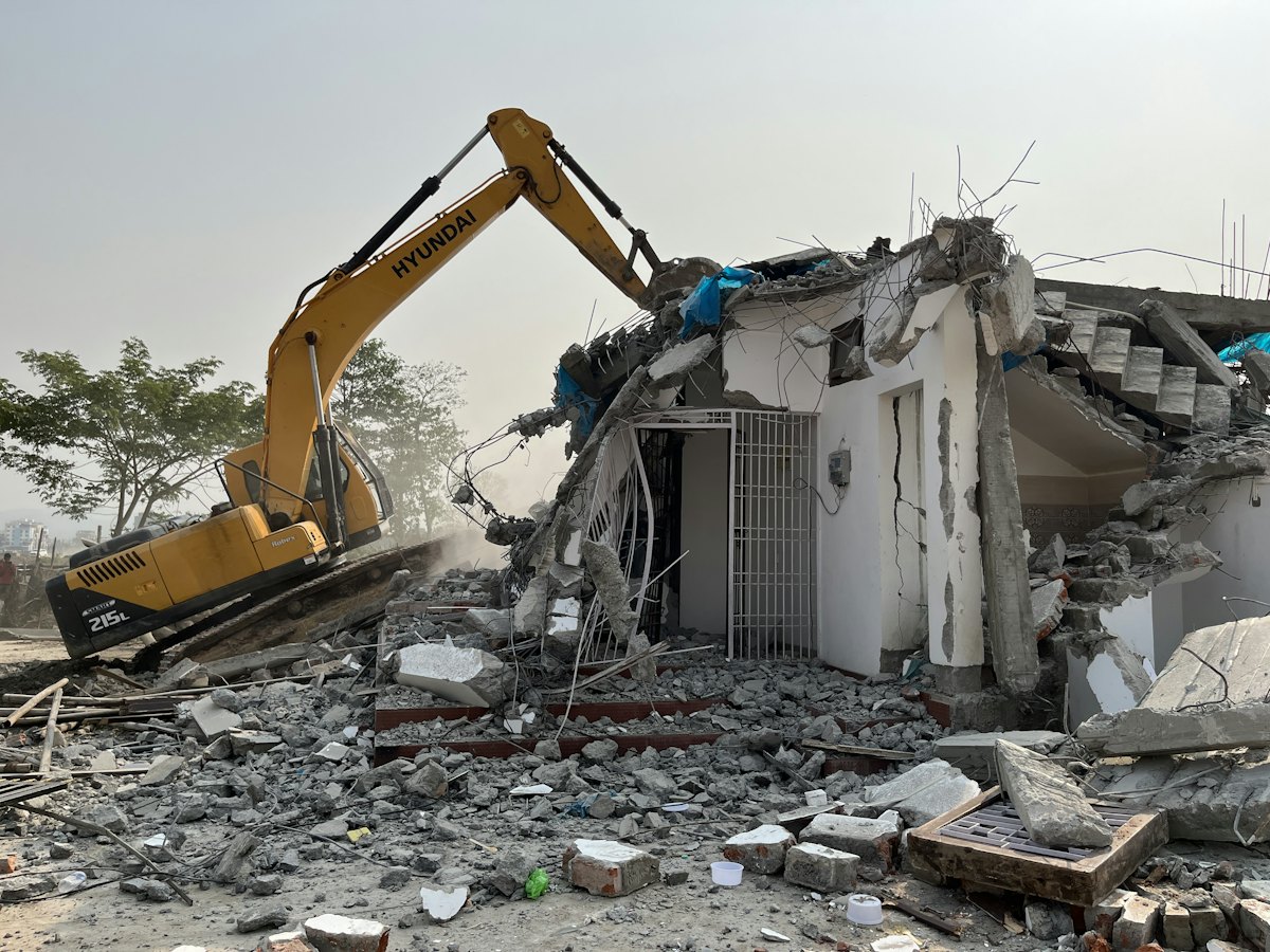 Excavator demolishing a house down to rubble