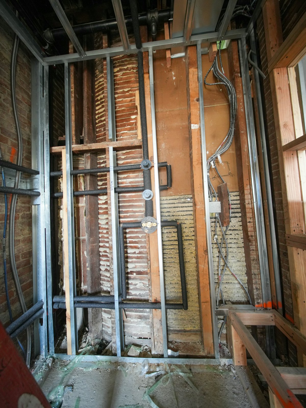 Opened-up wall exposing old wiring, pipes and building materials