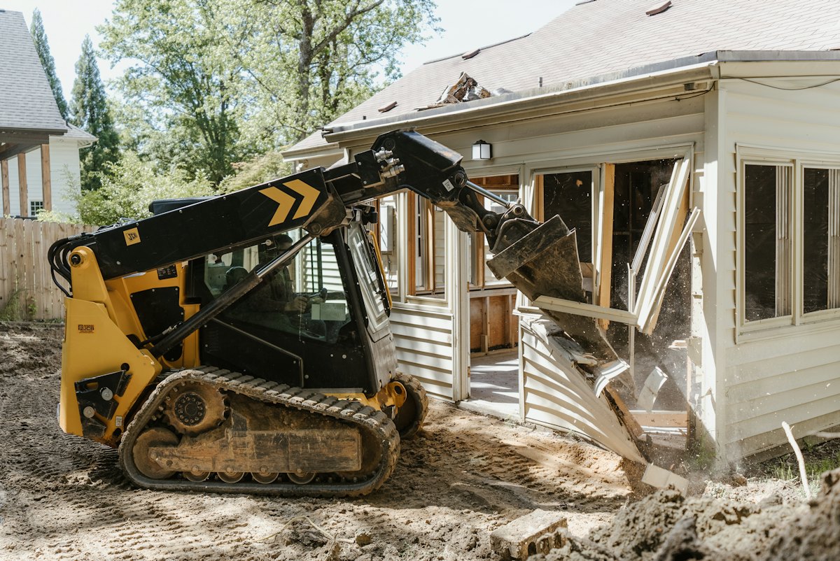 Skid steer clearing debris from a house demolition site