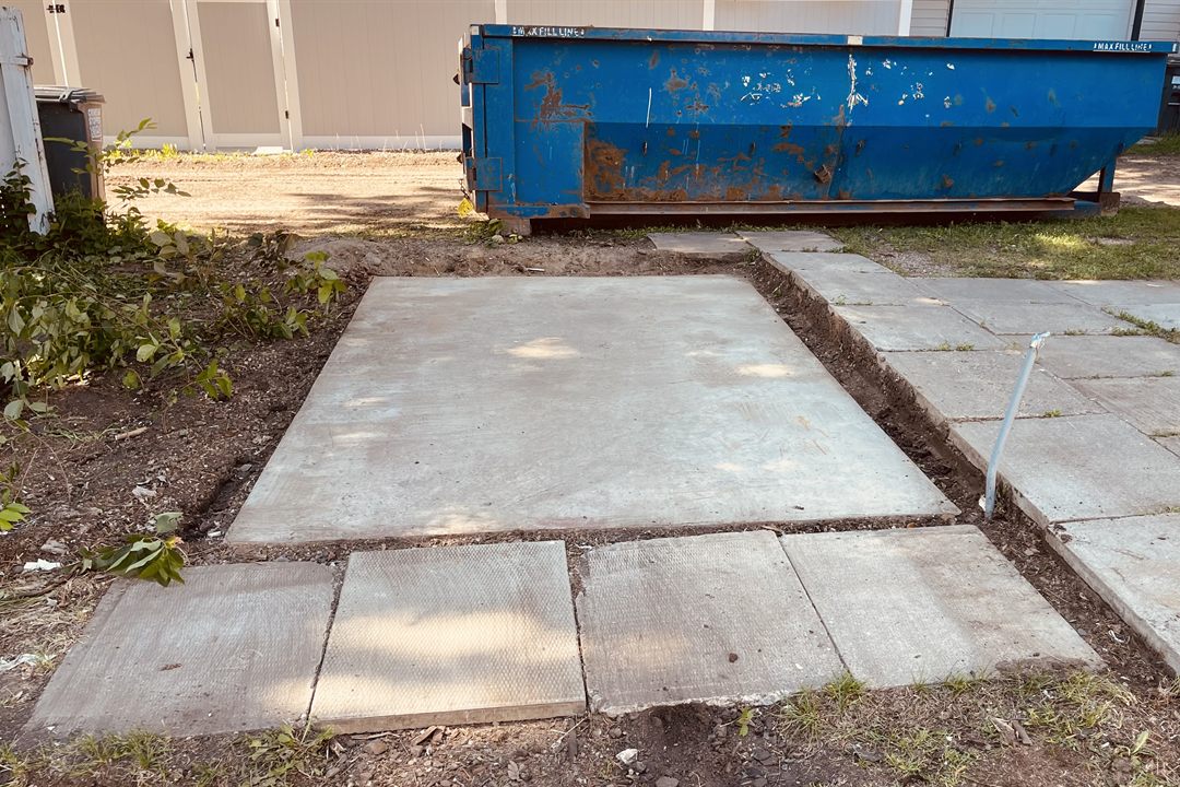 After shed removal by Demolition King Group: the shed taken down, leaving a clear concrete pad, with the debris bin in the back lane